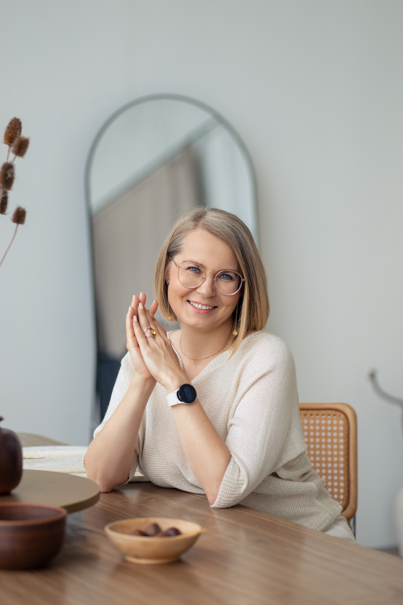 Ekaterina Rayzman sitzt lächelnd am Tisch mit gefalteten Händen